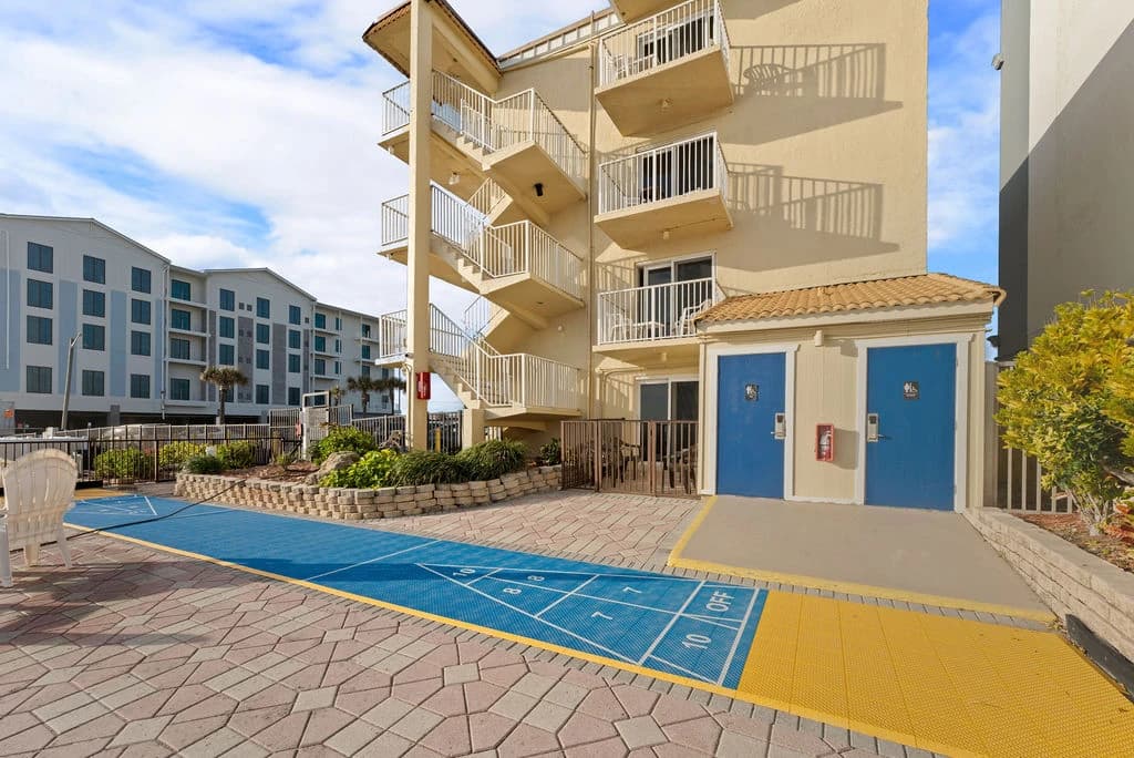 Oceanfront view between two beachfront buildings with parking lot and waves beyond.