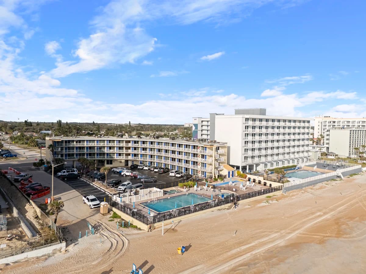 Wide sandy beach with rolling ocean waves under a bright blue sky.