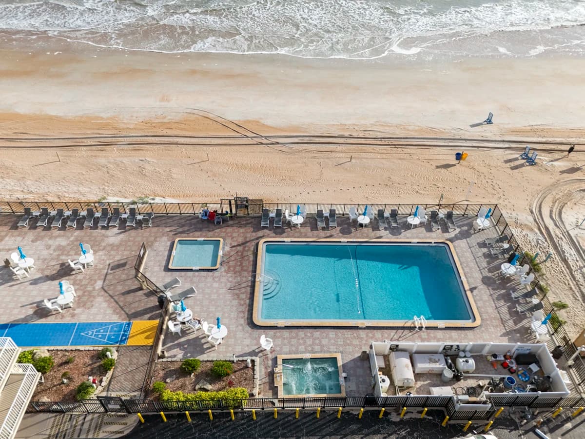 Beachfront property with a pool, hot tub, and direct access to sandy shores.